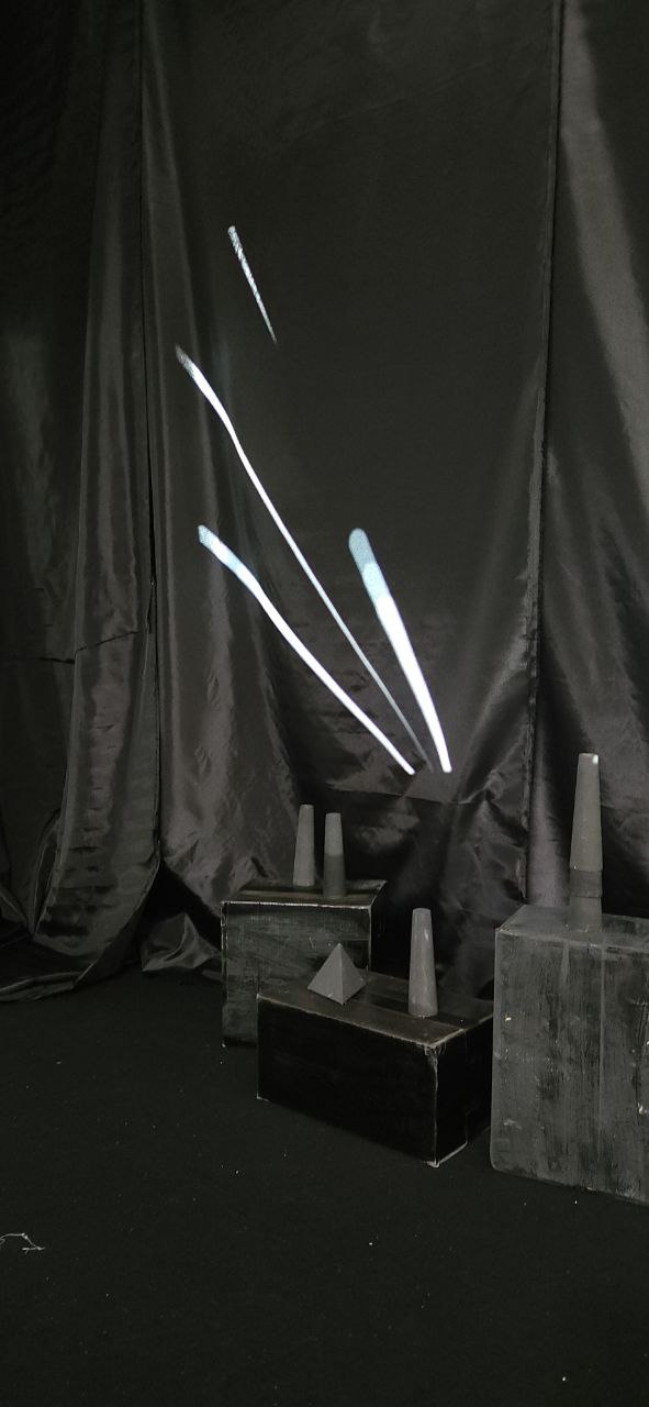 Projected light streaks on black fabric with sculptural forms